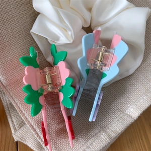 Vue détaillée de deux pinces à cheveux florales en acétate rose et bleu sur du lin