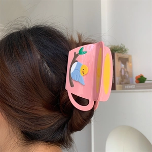 Detailed view of a pink cup-shaped hair claw clip with bird motif worn on a bun hairstyle