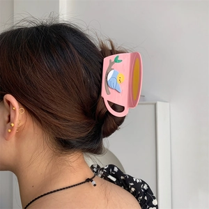 Pink coffee cup hair claw clip with blue bird relief worn on a brunette updo hairstyle