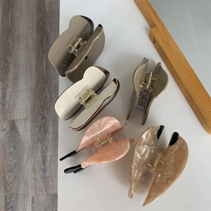 Primo piano di cinque mollette per capelli in acetato in vari colori e motivi marmorei
