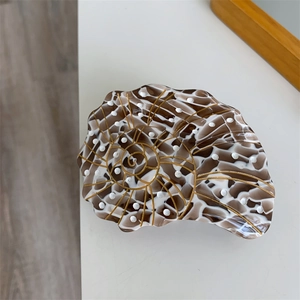 Detailed macro view of acetate hair claw showing shell shape with gold spiral line patterns
