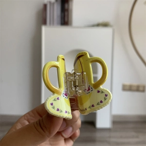 Close-up of yellow cowboy boot shaped acrylic hair claw clip with floral patterns
