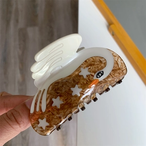 Detailed view of swan-shaped acetate hair claw clip with white and tortoiseshell pattern