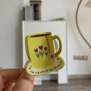 Detail of yellow coffee cup claw clip featuring floral tulip patterns and smooth acrylic finish