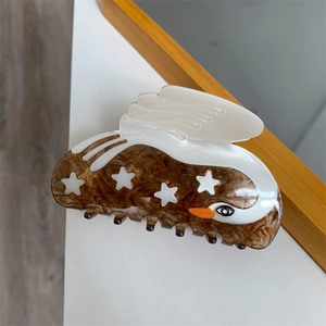 Macro detail of swan shaped acetate hair claw featuring brown marble pattern and white stars