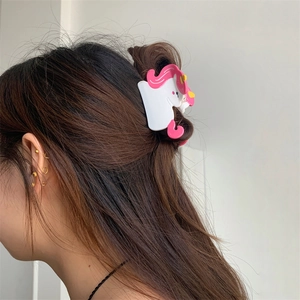 Detail of creative unicorn hair claw clip in pink and white on a model's hair