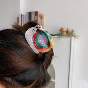 Détail de la pince à cheveux créative en forme d'escargot coloré sur cheveux bruns