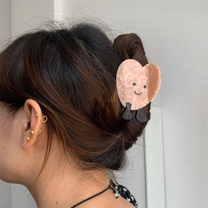 Primo piano di una pinza per capelli a cuore rosa in acetato con una simpatica faccina
