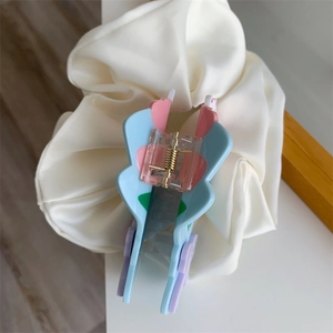 Détail d'une pince à cheveux en acétate rose et bleu avec ressort sur chouchou en soie