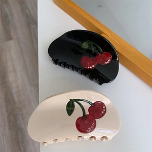 Detailed view of black and beige cherry hair claws with sparkling rhinestone accents