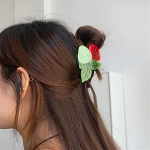 Vue détaillée d'une pince à cheveux fraise en acétate sur une femme aux cheveux bruns