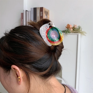 Détail de la pince à cheveux en acétate forme escargot aux anneaux colorés nacrés