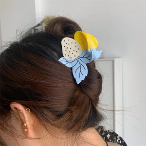 Détail d'une pince à cheveux en forme de fraise avec boucle d'oreille dorée multicouche