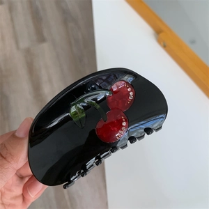 Close-up of cherry hair claw clip with rhinestones on black acetate hair accessory