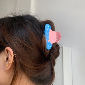 Pink and blue creative cartoon dolphin hair claw clip shown on dark brown hair