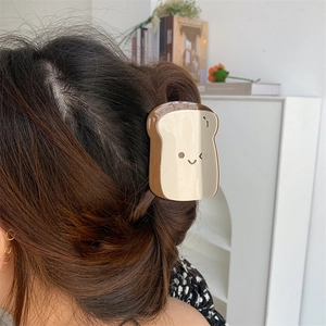 Vista dettagliata del fermaglio a forma di toast con sorriso sui capelli castani