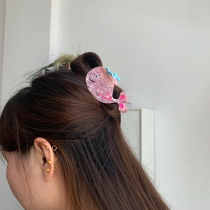 Pink whale-shaped acetate hair claw clip showing glossy marble texture in use