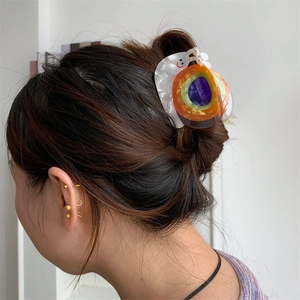 Détail de la pince à cheveux en acétate multicolore en forme d'escargot sur une femme