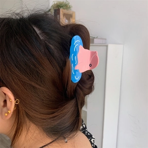 Close-up of a pink and blue dolphin acetate hair claw clip worn on a woman's hair