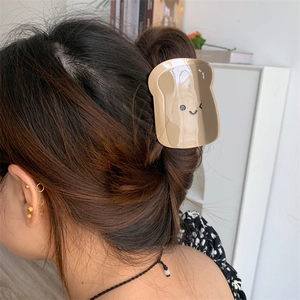 Dettaglio della molletta per capelli a forma di toast con un sorriso carino indossata