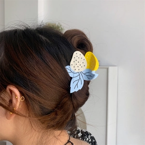 Vue latérale d'une pince à cheveux fraise bleue et jaune sur une coiffure