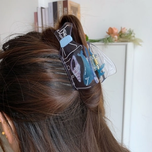 Detail view of a blue bottle-shaped acetate hair claw featuring whale and seashell motifs