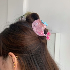 Detailed view of a pink whale hair claw clip made of premium acetate on dark hair