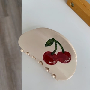 Detail of cream hair claw clip with cherry motif and sparkling rhinestones
