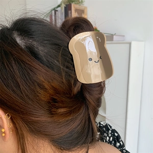 Dettaglio di un fermaglio per capelli a forma di toast a cartone su lunghi capelli scuri
