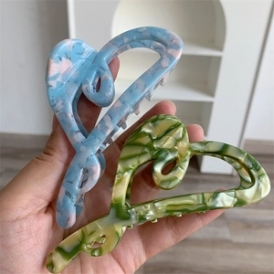 Detail showing heart-shaped acetate hair claws in blue pink and yellow green marble patterns