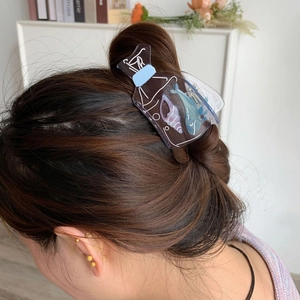 Blue ocean-themed hair claw clip with whale and seashell pattern shown in a hair bun