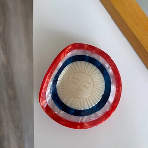 Close-up of a round acetate hair claw featuring a smiling sun pattern with marble texture