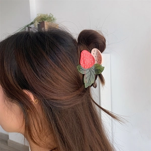 Détail d'une pince à cheveux en acétate en forme de fraise sur une coiffure