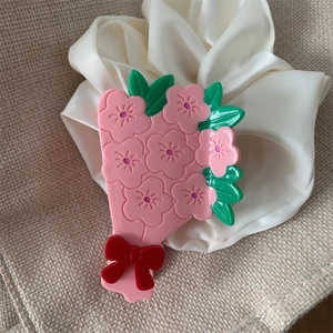 Vue détaillée de la pince à cheveux bouquet de fleurs roses avec un décor de nœud rouge