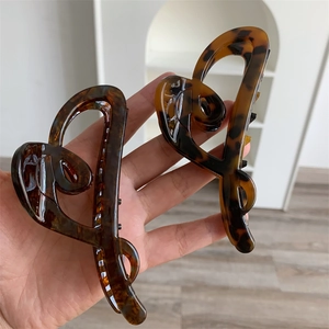 Detail of two heart-shaped acetate hair claws with brown leopard print and glossy finish