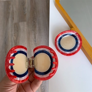 Detailed close-up of retro acetate hair claw with red, white, and blue concentric circles