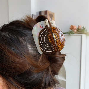 Gros plan d'une pince à cheveux créative en forme d'escargot avec effet nacre sur la coiffure