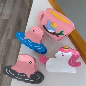 Close-up of cute cartoon hair claws including pink bird, blue dolphin, and white unicorn
