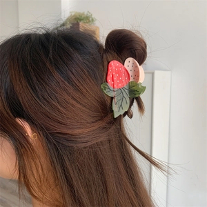 Détail d'une pince à cheveux en acétate en forme de fraise sur cheveux bruns