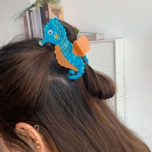 Detail of a blue seahorse hair claw clip made of marble texture acetate on model