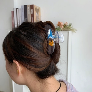 Detail view of large acetic acid shark hair claw clip used in a stylish bun hairstyle