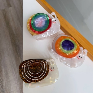 Détail de pinces à cheveux escargot en acétate aux motifs colorés et imprimé léopard
