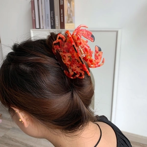 Détail d'une grande pince à cheveux crabe avec texture marbrée orange sur cheveux longs