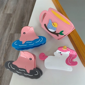Detailed view of four colorful acetic acid hair clips featuring dolphins and unicorns