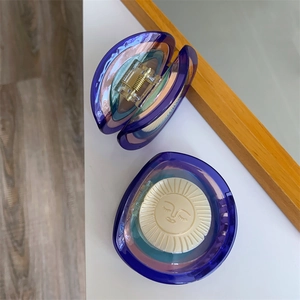 Detail of blue acetate hair claw clip featuring a 3D sun face design and metal spring