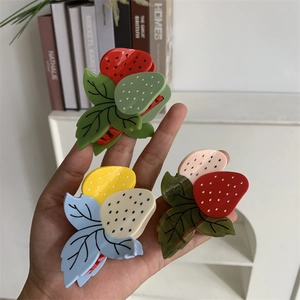 Détail de trois pinces à cheveux en forme de fraise en acétate brillant coloré
