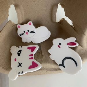 Gros plan de barrettes mignonnes en acétate en forme de chat et lapin sur plateau