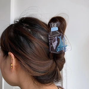 Detail of whale and seashell acrylic hair claw clip used on a brunette messy bun hairstyle