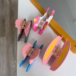 Detailed view of four colorful cartoon-style acetate shark hair claws on a white desk