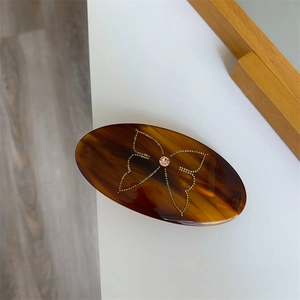 Detail of tortoise shell oval hair clip with gold bead butterfly and pink crystal